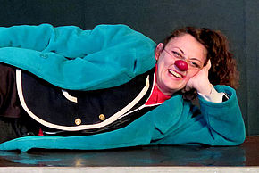 Photo de l'artiste Elena Adragna, allongée au sol avec un nez de clown