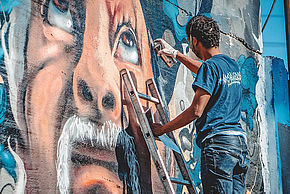 Photo d'un graffeur à l'œuvre sur la façade d'un immeuble - Agrandir l'image