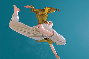 Photo d'une danseuse dans les airs sur fond bleu turquoise
